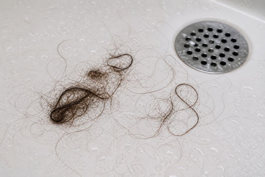 chute de cheveux visible sous la douche avec mèches accumulées près de l’évacuation